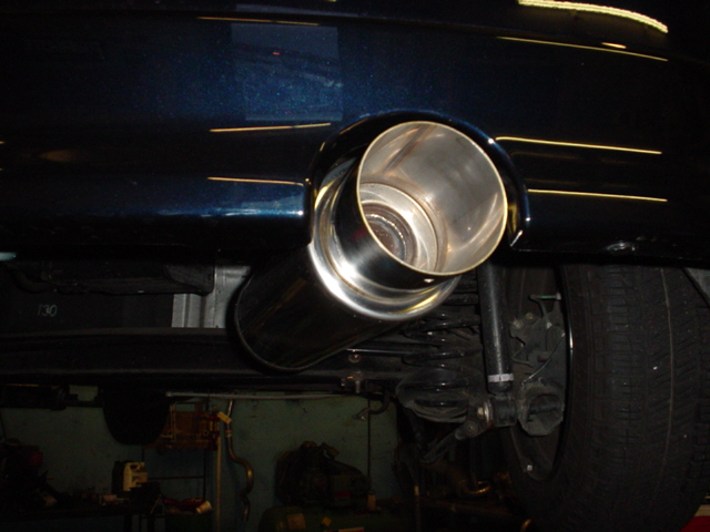 Dark blue car's chrome exhaust pipe and tire, viewed from below