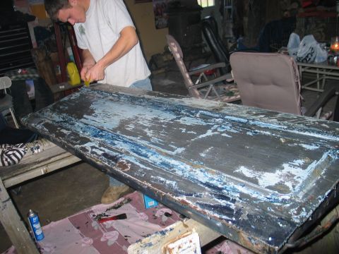 1995 Ford Bronco - A person scrapes old paint off a large door.