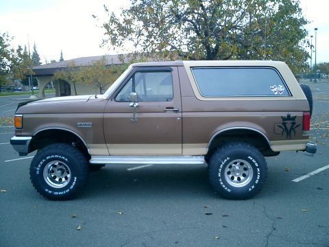 1990 Ford Bronco - This lifted Ford Bronco features a two-tone brown paint job and large off-road tires.