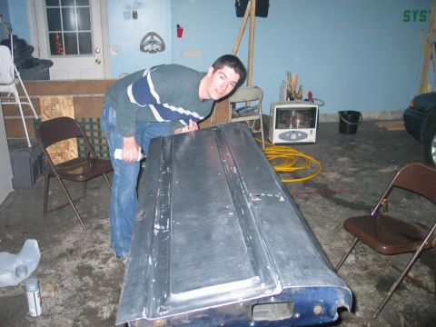 1995 Ford Bronco - A person works on a silver tailgate with blue trim in a garage setting.