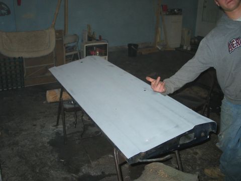 1995 Ford Bronco - A person points at a gray primed tailgate resting on sawhorses in a workshop.