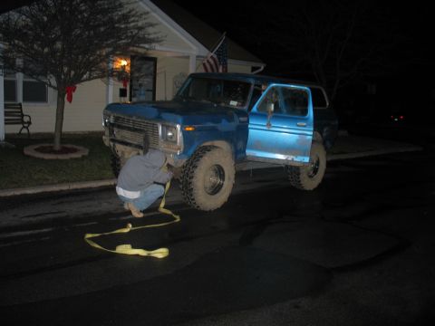 1995 Ford Bronco - Night shot of a blue full-size Ford Bronco with a removable hardtop sitting in a wet residential street, lifted on mud-terrain tires with c…