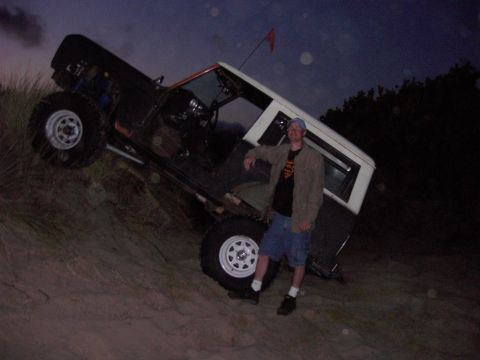 1980 Ford Bronco - A man poses next to a lifted 1978 Ford Bronco on a sandy dune at dusk.