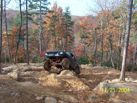 1978 Ford Bronco - An off-road vehicle tackles a challenging rocky trail amidst autumn foliage.