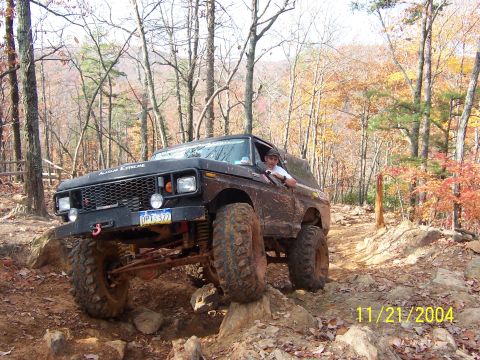 1978 Ford Bronco - A 1978 Ford Bronco navigates a challenging off-road course with autumn foliage in the background.