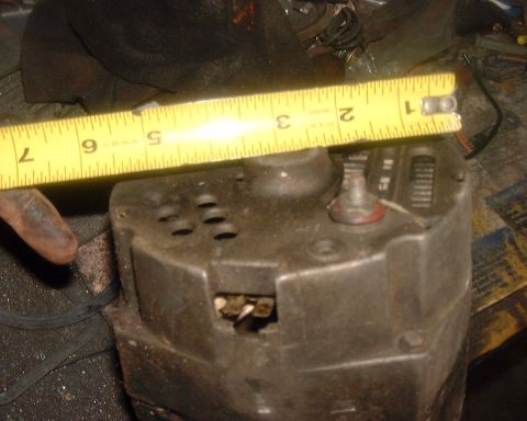 1985 Ford F-150 - A close-up view of an alternator, with a yellow measuring tape placed across its top surface.