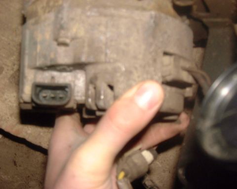 1985 Ford F-150 - Close-up of a used car alternator, likely being removed or installed.
