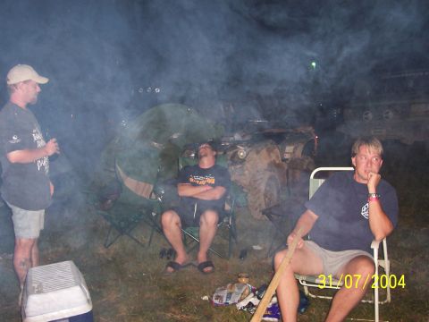 1979 Ford F-150 - People relax around a campfire with off-road vehicles in the background.