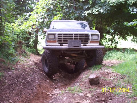 1979 Ford F-150 - A lifted 1979 Ford F-150 navigates a rough, wooded trail with a custom front bumper.