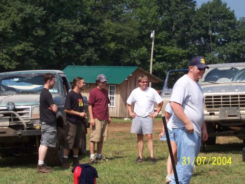 1979 Ford F-150 - Several men gather around two Ford trucks in a grassy outdoor setting.