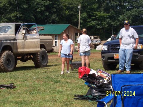 1979 Ford F-150 - A group of people stand around vehicles in a grassy outdoor area on a sunny day.