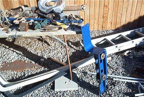 1986 Ford Bronco - A blue metal bracket is visible on the ground, surrounded by various parts and tools.