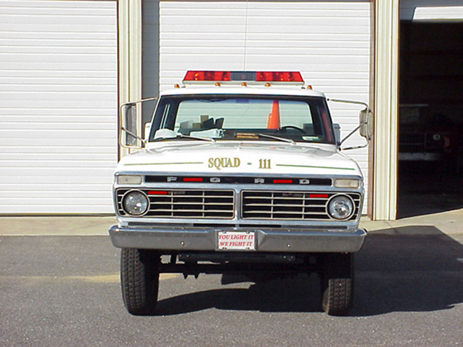White 1970s Ford squad truck with roof light bar and SQUAD 111 hood lettering