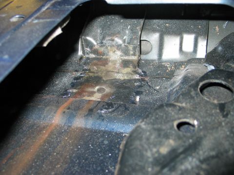 1995 Ford Bronco - Detail of a vehicle's interior floor, revealing areas of rust and repair work.