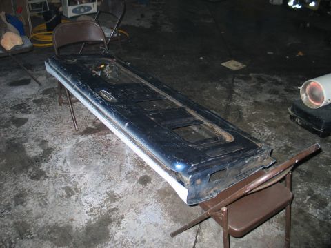 1995 Ford Bronco - A car door is placed on chairs in a workshop setting.