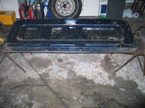 1995 Ford Bronco - A detached vehicle tailgate is shown indoors, supported by chairs.