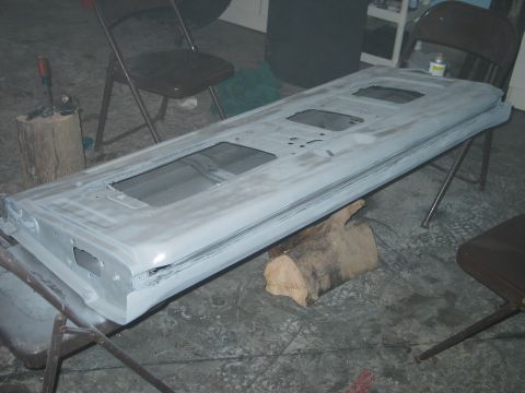 1995 Ford Bronco - A gray tailgate, likely undergoing restoration, is displayed on sawhorses in a workshop setting.
