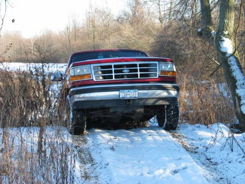 1995 Ford Bronco - A red 1995 Ford Bronco navigates a snowy, wooded path.