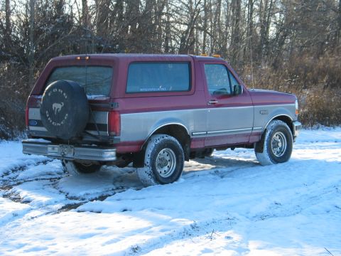 1995 Ford Bronco - Maroon and silver two-tone 1995 Ford Bronco with a spare tire on the back, parked in the snow.