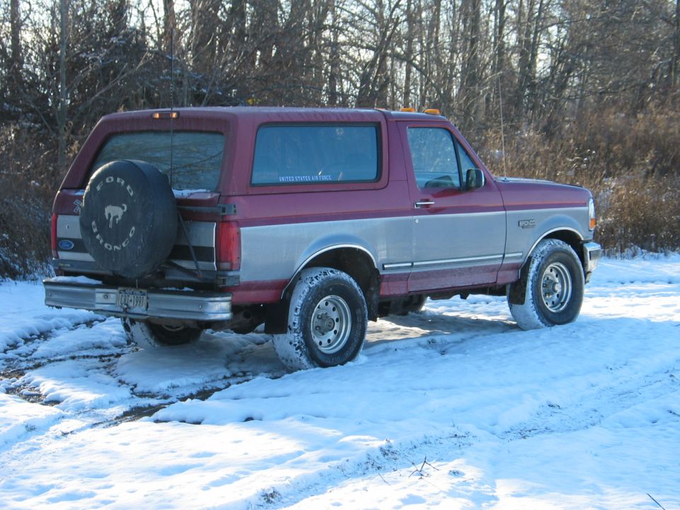 1995 Ford Bronco parked on a snowy dirt road, spare tire on rear door