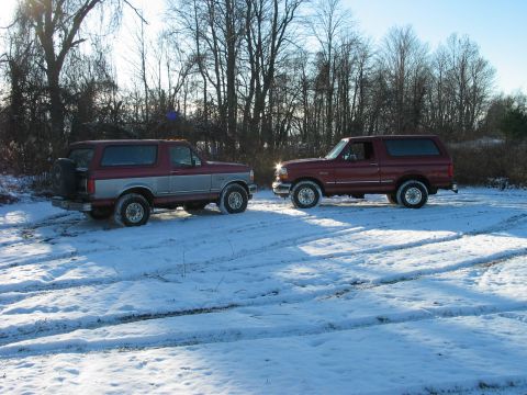 1995 Ford Bronco - Two Ford Broncos are parked in a snowy field under a clear sky.
