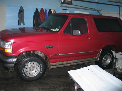1995 Ford Bronco - Side view of a red 1995 Ford Bronco parked indoors.