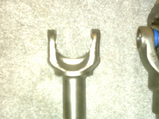 Driveshaft U-joint yoke ends laid on carpet, fresh blue plastic seals visible on the caps