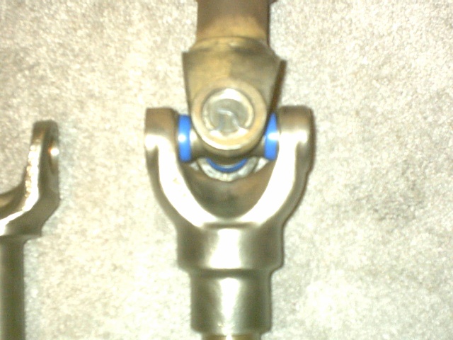 Assembled driveshaft U-joint connecting two yokes, blue seal rings on the bearing caps
