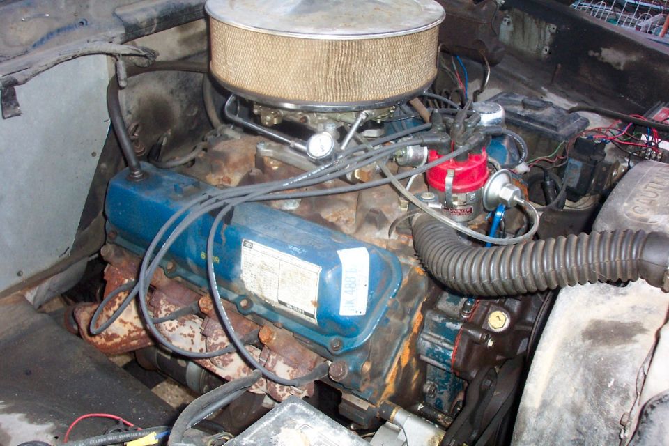 Ford V8 engine with blue valve covers, chrome round air cleaner, and red distributor cap