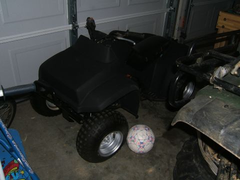 1978 Ford Bronco - A black ATV is parked next to another ATV in a garage.
