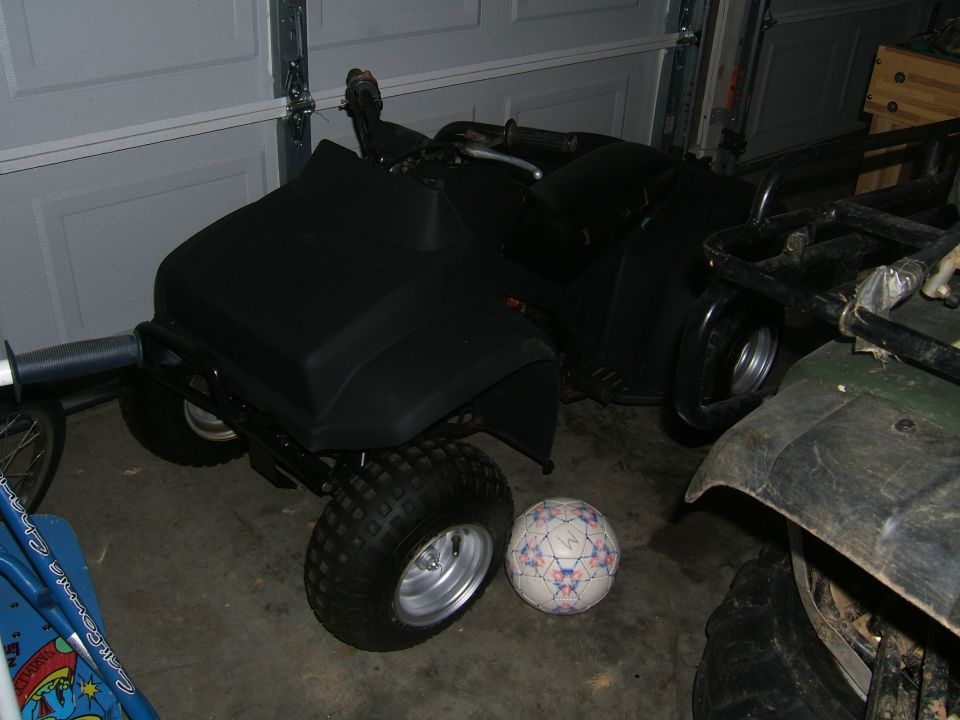 Black ATV with silver wheels and a soccer ball next to it