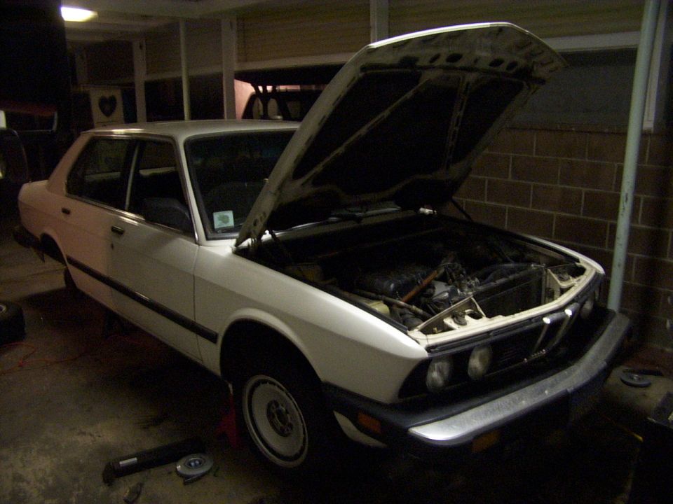 White sedan with hood open, showing engine bay
