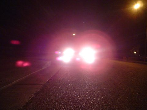 1993 Ford Taurus - A car's headlights illuminate a dark road at night, making it difficult to discern details.
