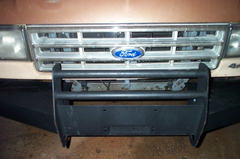 1987 Ford Bronco - The front of a Ford truck shows a grille with a Ford emblem and an aftermarket bumper with a winch mount.