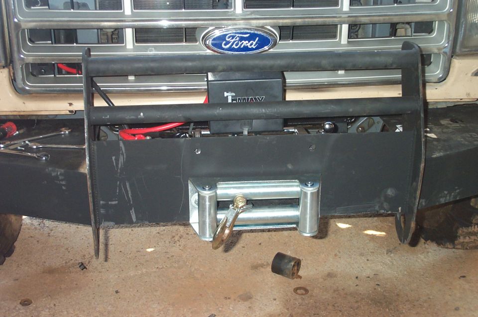 Ford truck front end with a black bull bar and winch, showing a "T-MAX" label and red cables