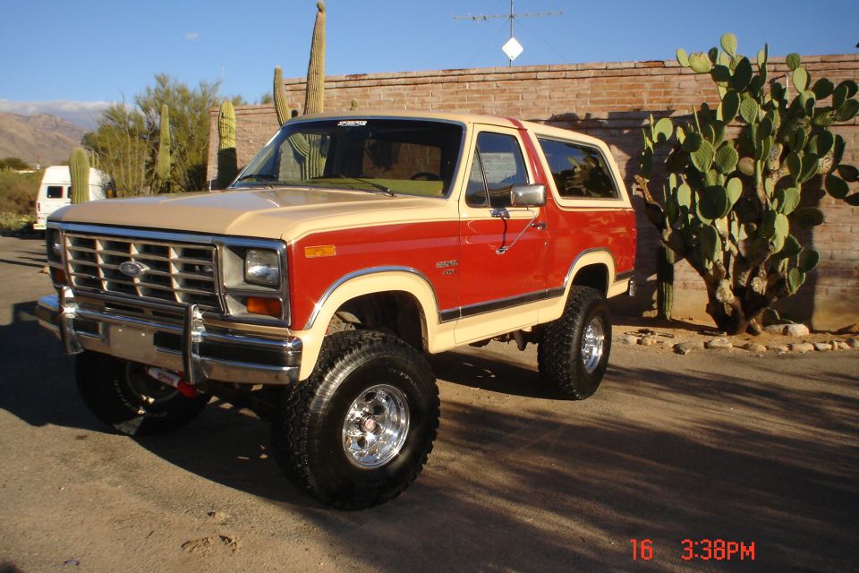 Red and tan Ford Bronco with a lift kit parked outdoors