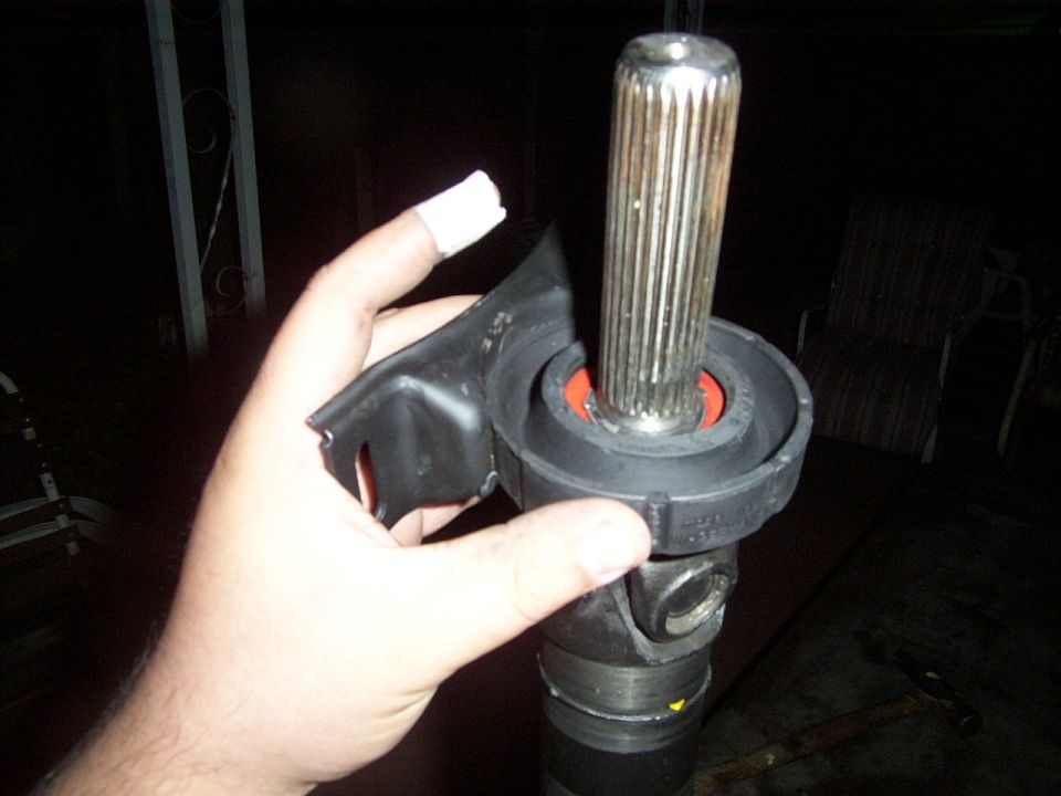 Hand holding a driveshaft U-joint and yoke with a splined shaft