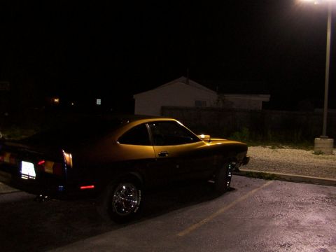 1978 Ford Mustang II - A two-tone Ford Mustang II is parked in a lot under a street light at night.