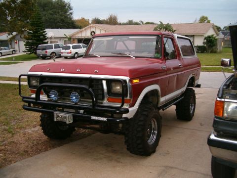 1979 Ford Bronco - Modified red Ford Bronco parked in a driveway, with another vehicle to its right.