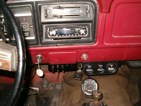 1979 Ford Bronco - The dashboard features a stereo, ignition, and multiple gauges, including a tachometer and three auxiliary gauges.