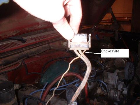 1986 Ford F-250 - Close-up of a choke wire connector in an engine bay, with a hand holding it.