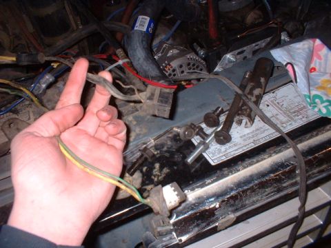 1986 Ford F-250 - A close-up view of a vehicle's engine bay shows a hand holding electrical wires near a diagram.
