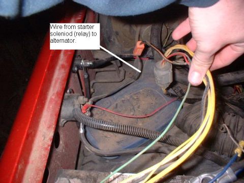 1986 Ford F-250 - Close-up of engine bay wiring with a hand manipulating wires near the battery.
