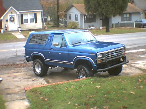 1984 Ford Bronco - This blue Ford Bronco is parked on the side of a residential street.