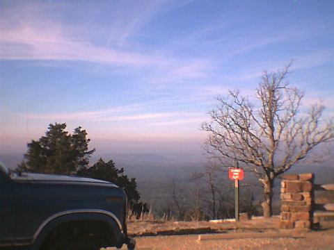 1984 Ford Bronco - A pickup truck is parked at a scenic overlook with a vast landscape stretching out below.