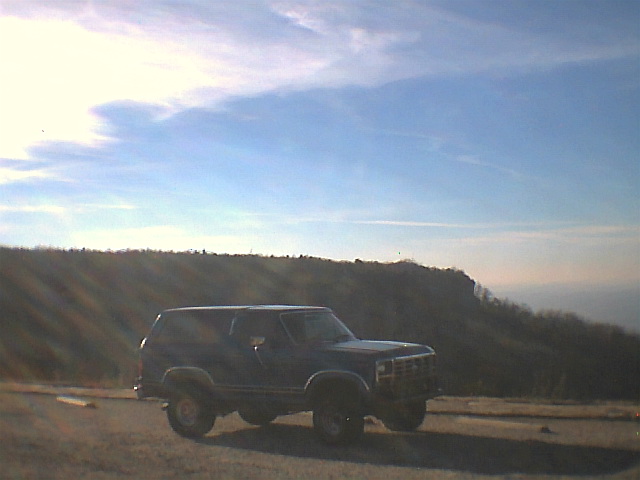 Dark SUV with a boxy body and prominent grille parked on a dirt road