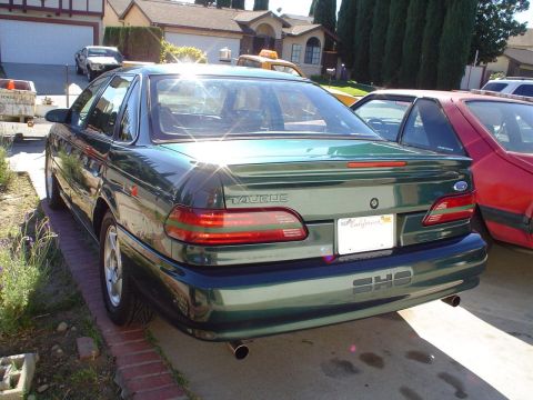 1993 Ford Taurus - Rear view of a green sedan with 'TAURUS' badging and a California license plate.