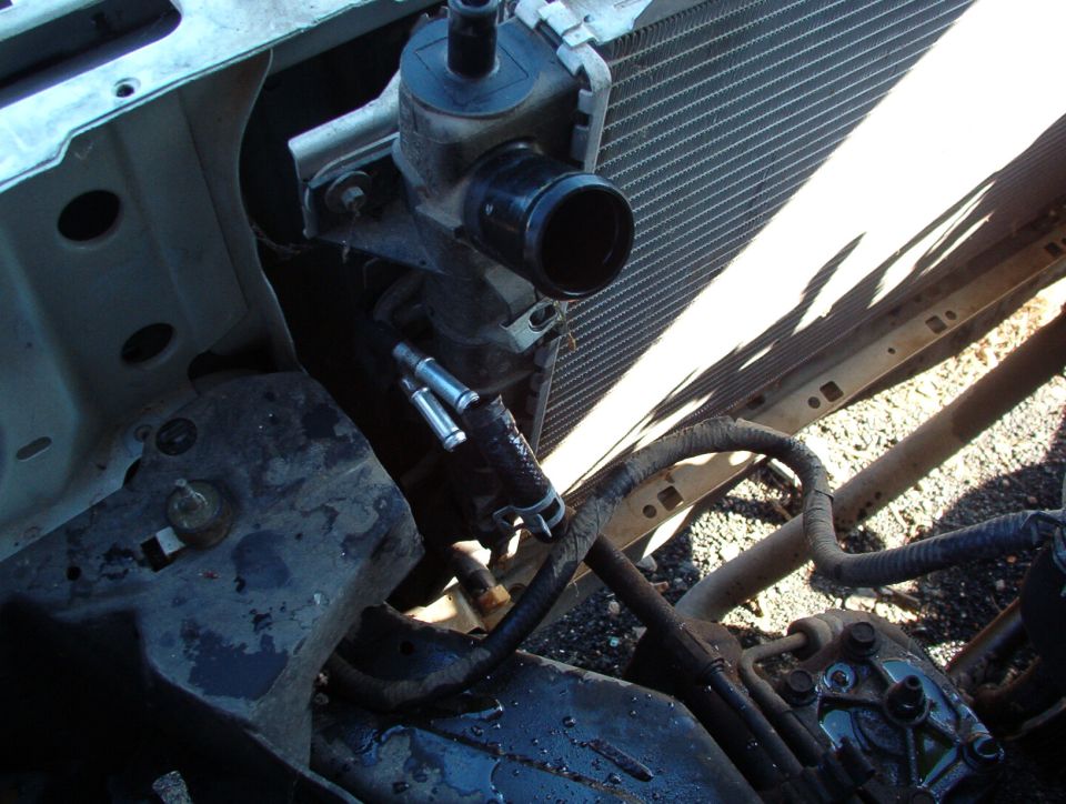 Radiator, thermostat housing outlet, and power steering lines on a partially disassembled vehicle