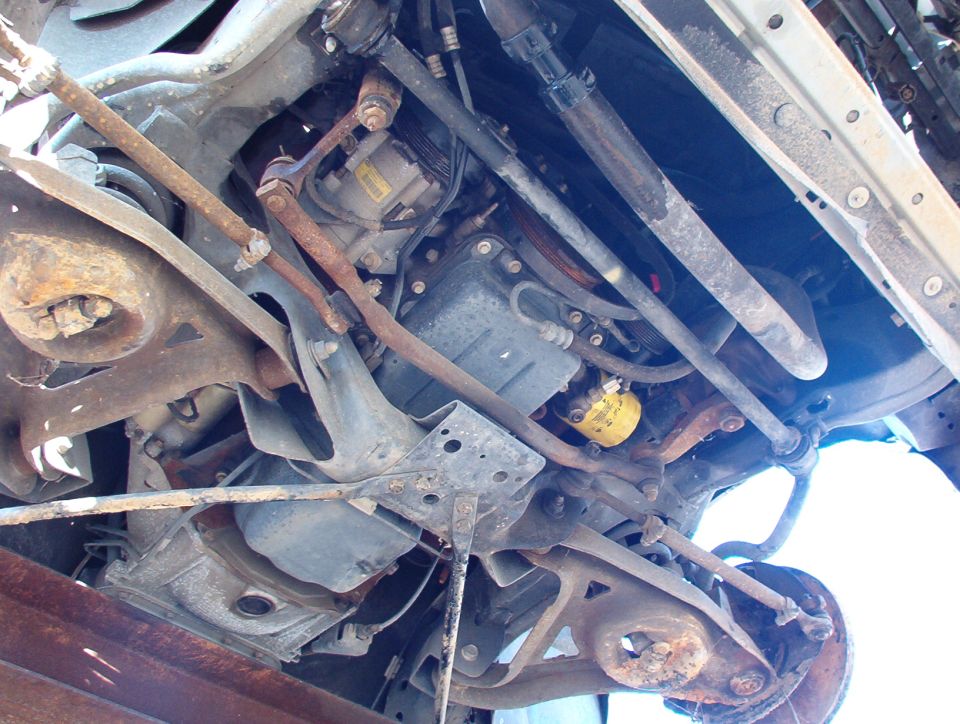 Rusty undercarriage showing front suspension, control arms, and coil spring