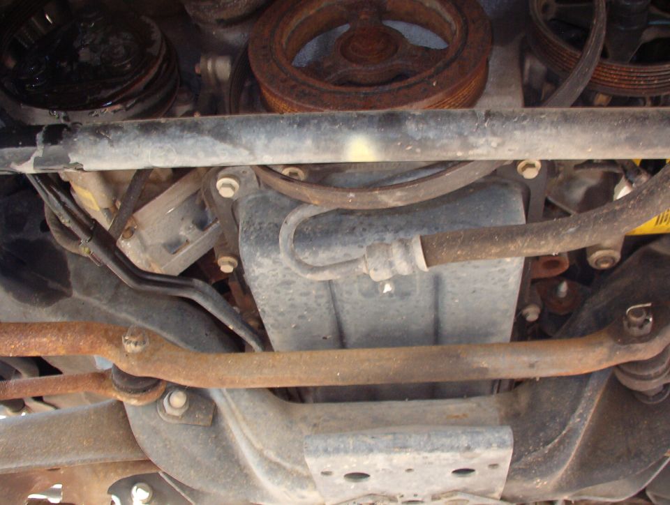 Undercarriage view of engine oil pan, crank pulley, and rusty steering linkage